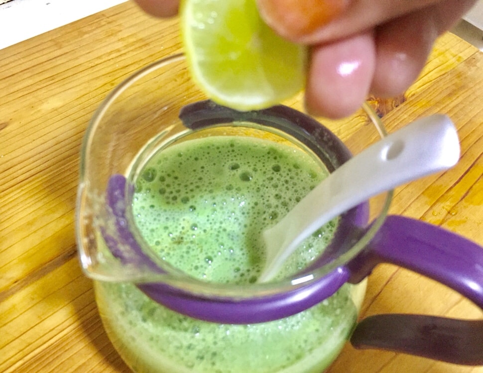 Cucumber juice in which a hand is squeezing lemon.