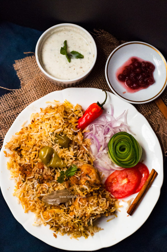 Pakistani chicken biryani served in plate withfresh salad chutney and raita on the side.