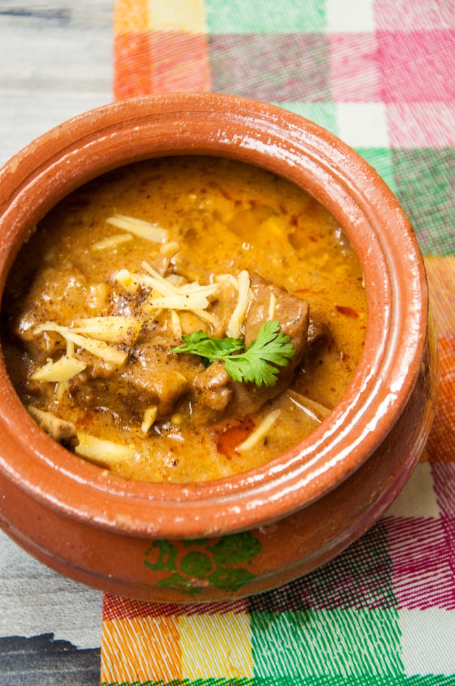 Mutton Kunna Gosht Served in a clay pot with ginger and cilantro garnish.