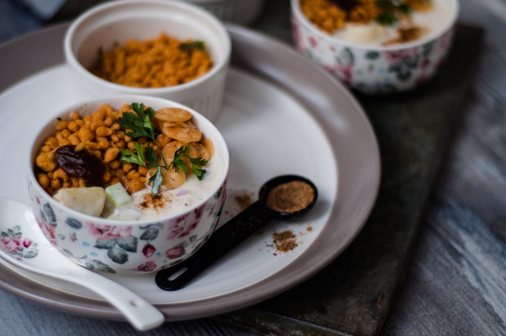 Three bowls of Boondi raita with chat masala on the side.