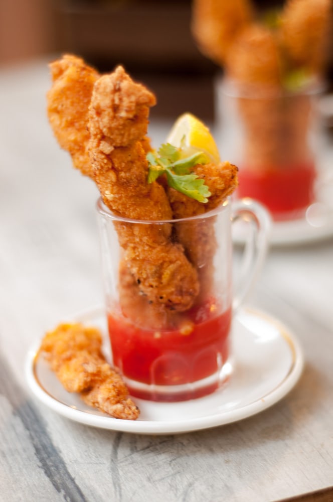 Cornflakes chicken strips served in a shot glass dipped in ketchup.