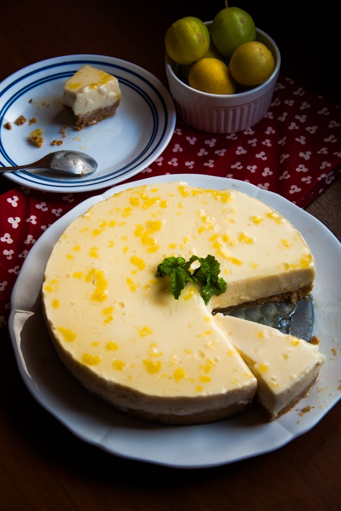 Lemon mousse cake served on a plate with a half eaten slice in the background.