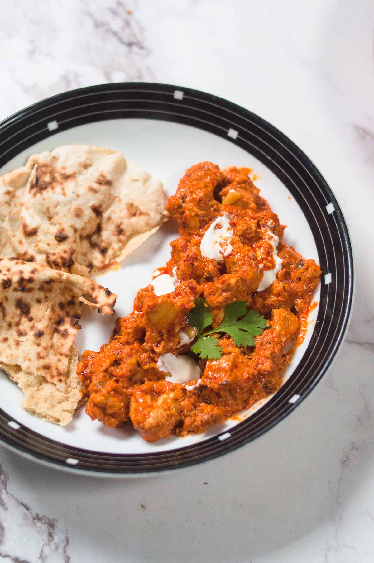 butter chicken served in a plate with naan.
