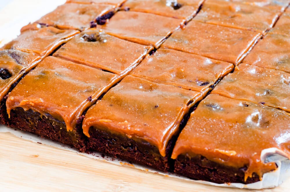 Brownie on baking paper, sliced in square portions.