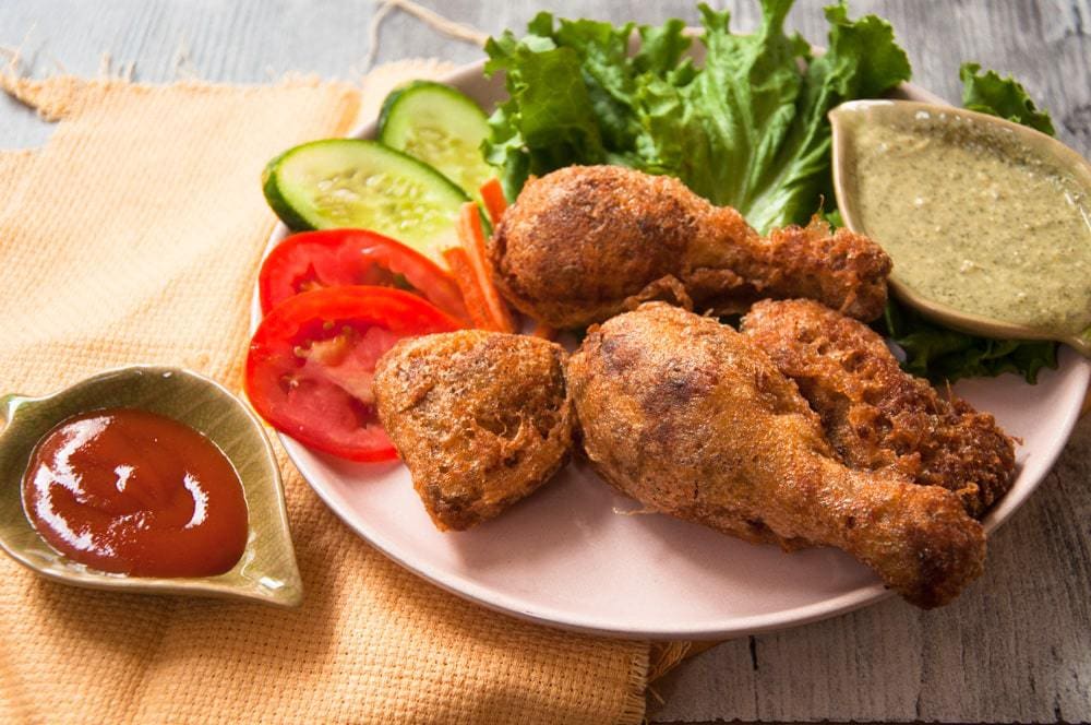 Fried chicken served in pink plate with salad and sauces.