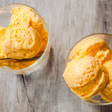 Top view of two cup of ice cream with scoops of mango ice cream.