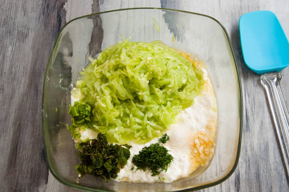 Ingredients of tzatziki sauce placed in a bowl.