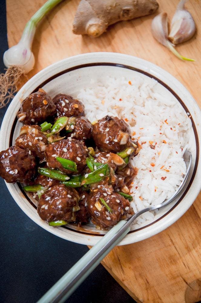 Asian glazed meatballs served in a bowl with plain rice.