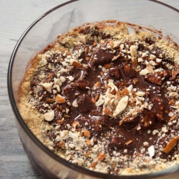 Chocolate biscuit pudding served in bowl with nuts garnish.