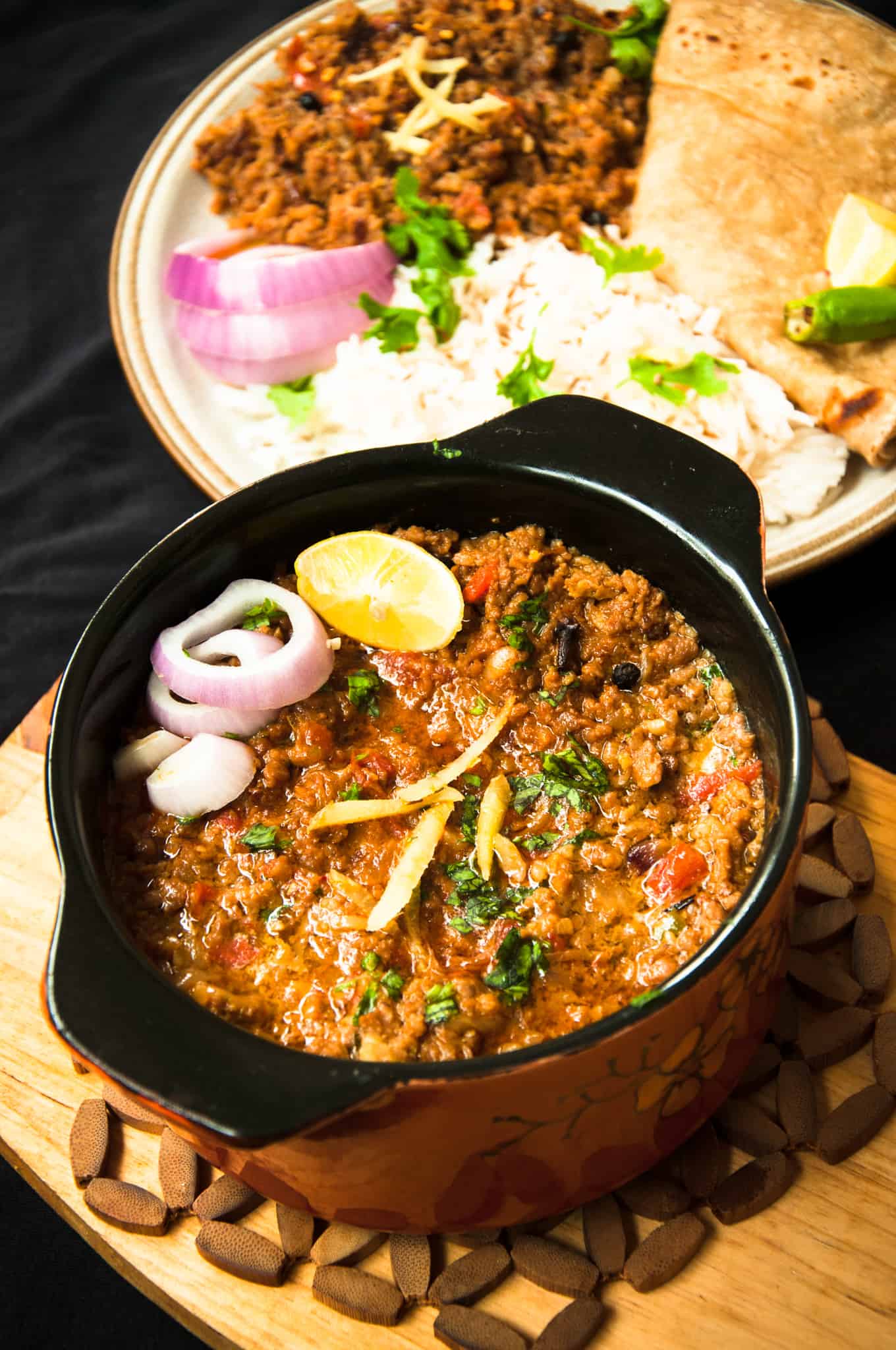 Keema serves in a bowl with roti and rice in the background.