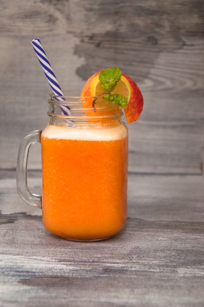 Peach drink served in a small pitcher with lemon slice, peach slice and straw.