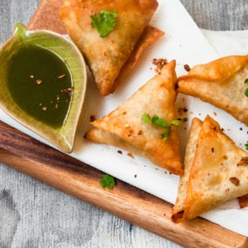 Fried Beef samosa served on tissue with cilantro leaves garnish.