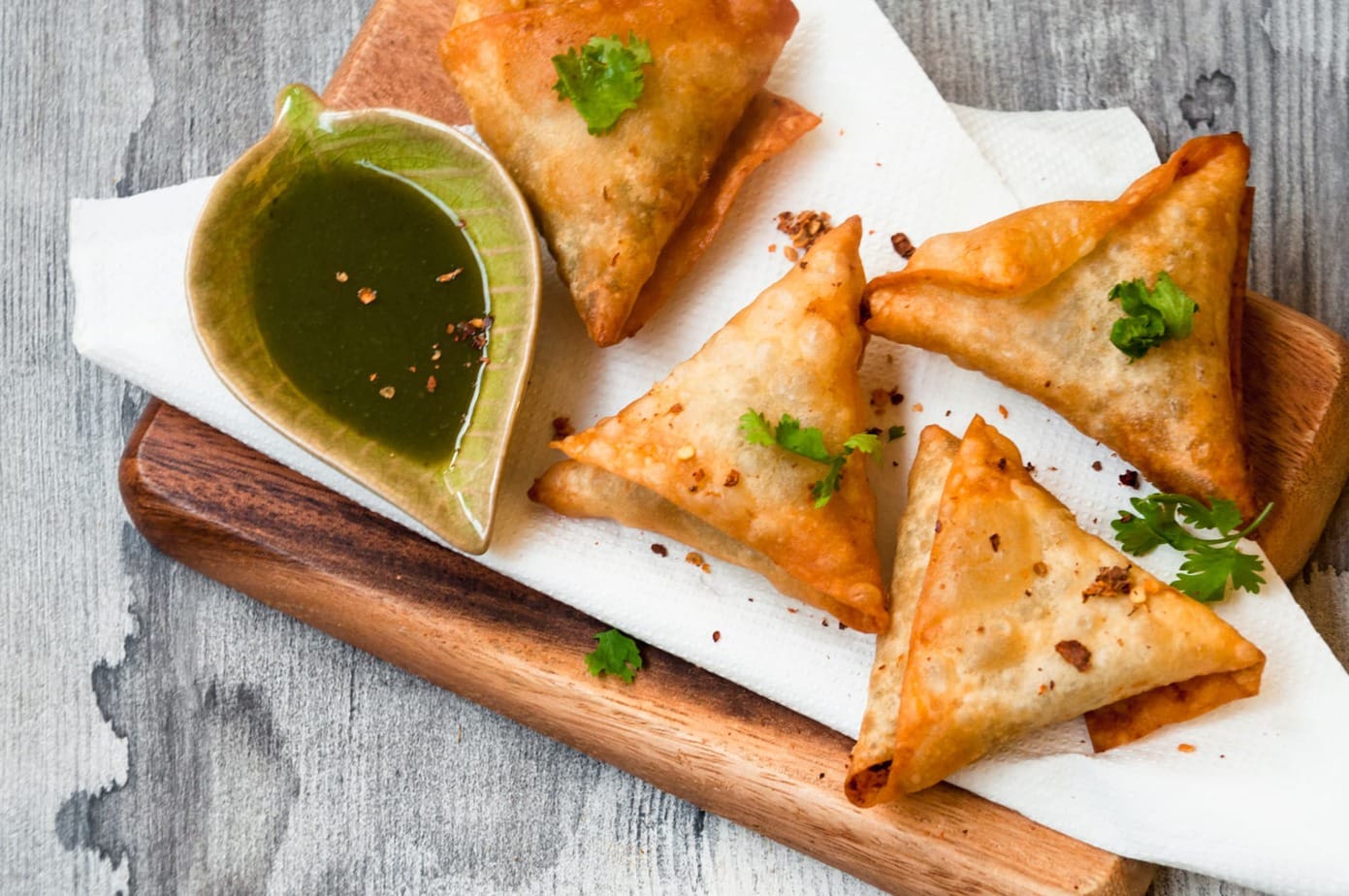 Fried Beef samosa served on tissue with cilantro leaves garnish.