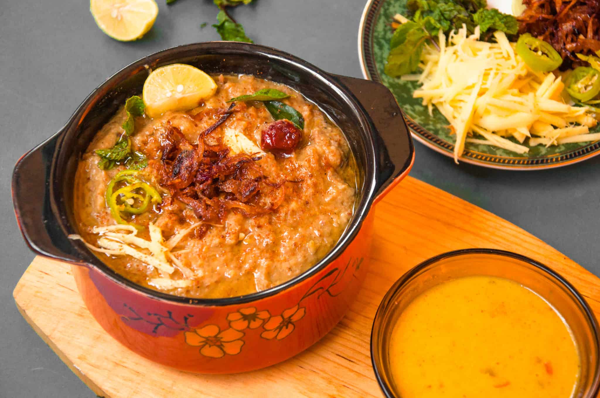 Haleem served with lemon wedges, kadhi, ginger, mint and fried onions.