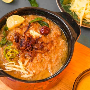 Haleem served in small serving pot with garnish.