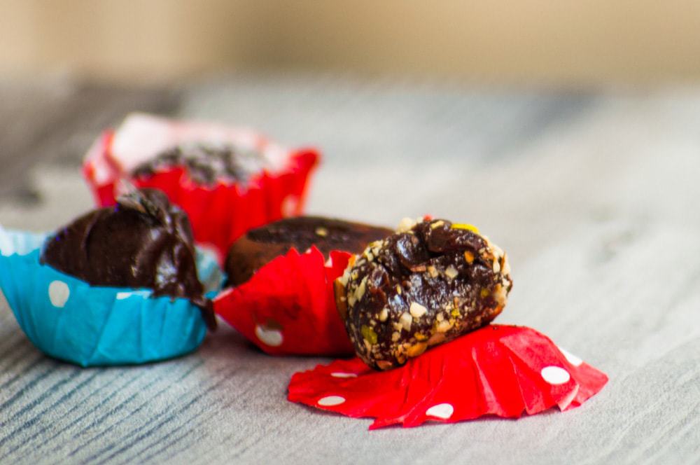 A half chocolate condensed truffles resting on the red bon bon cup, teeth marks are visible.