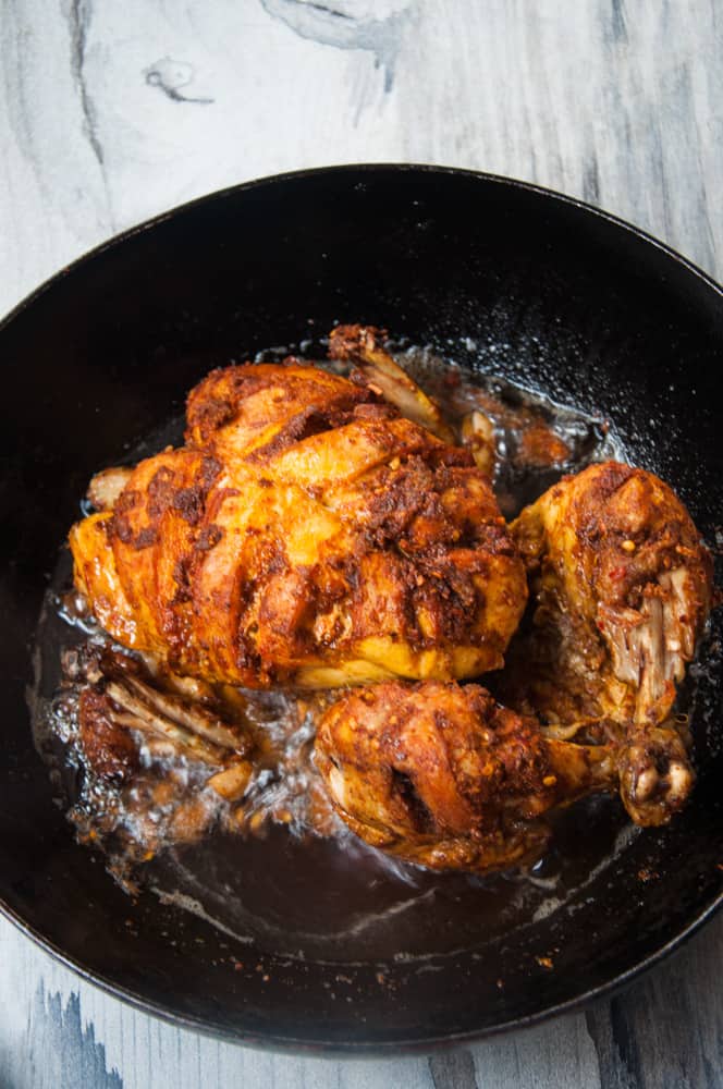 Charga chicken in a wok with oiling bubbling on the sides.