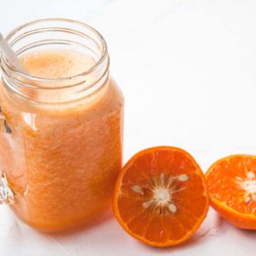 Orange juice served with orange halves on the side.