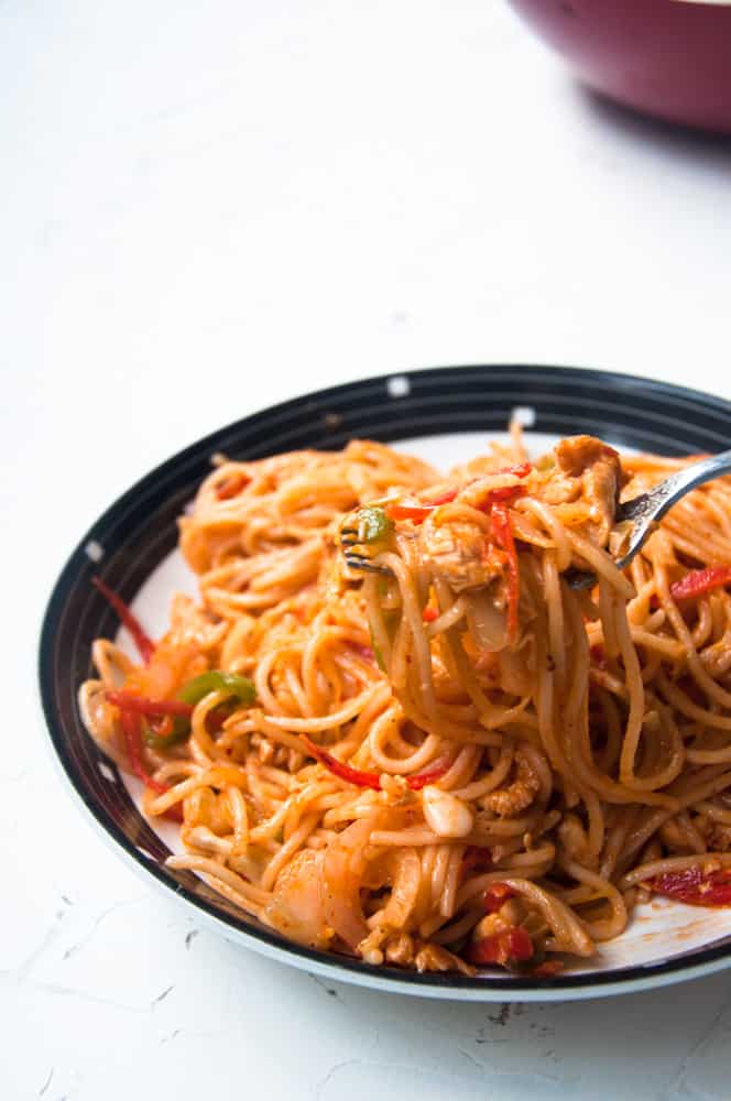 Pakistani desi Chow mein served in a plate with a bite in a fork.