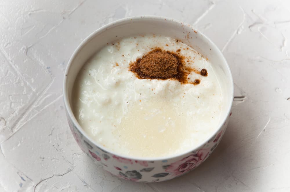 Yogurt with sugar and chaat masala in a white bowl.