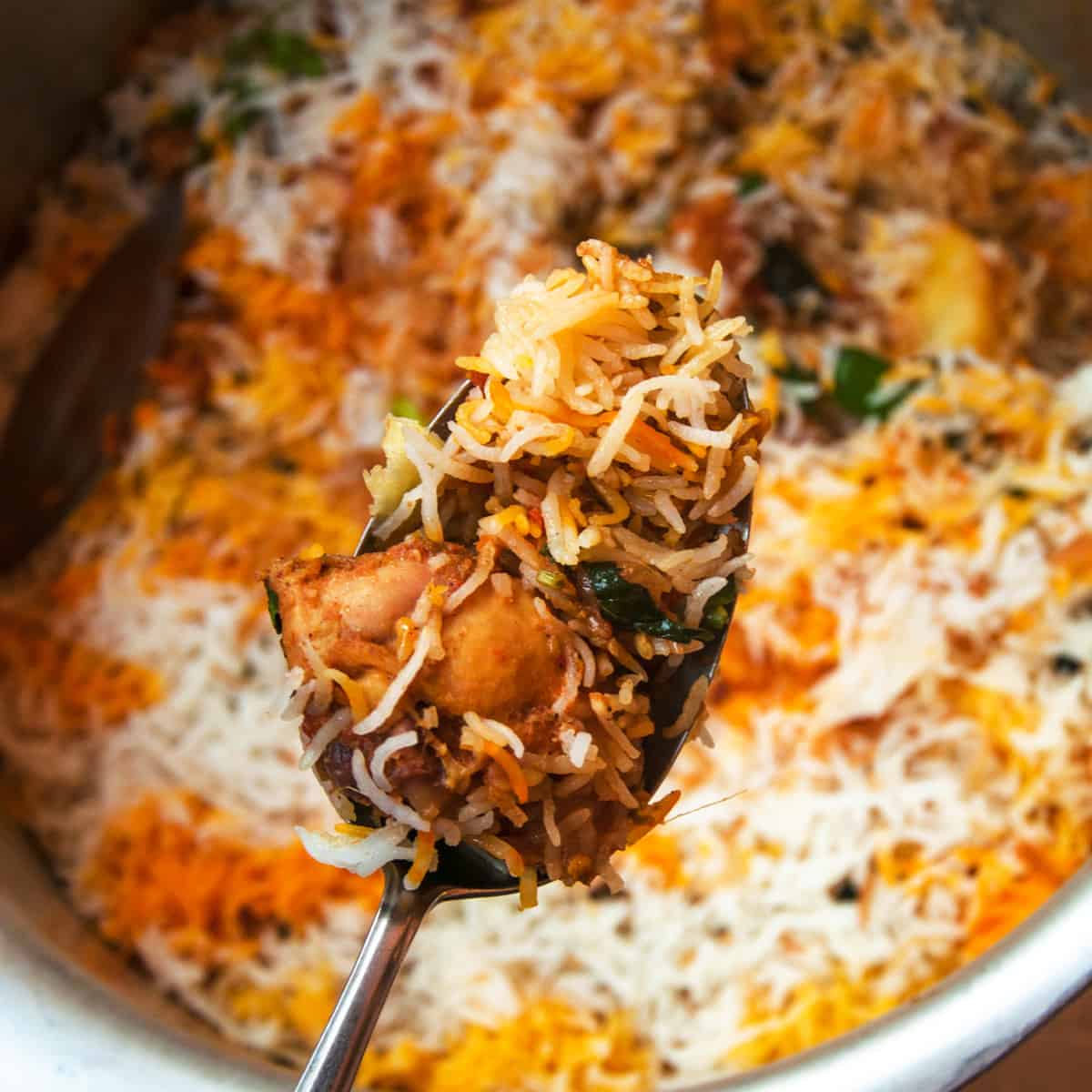 A close of spoon filled with biryani.