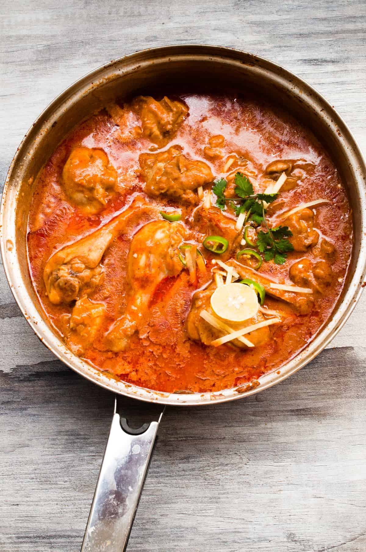 Nihari i the pan with garnish on the top.