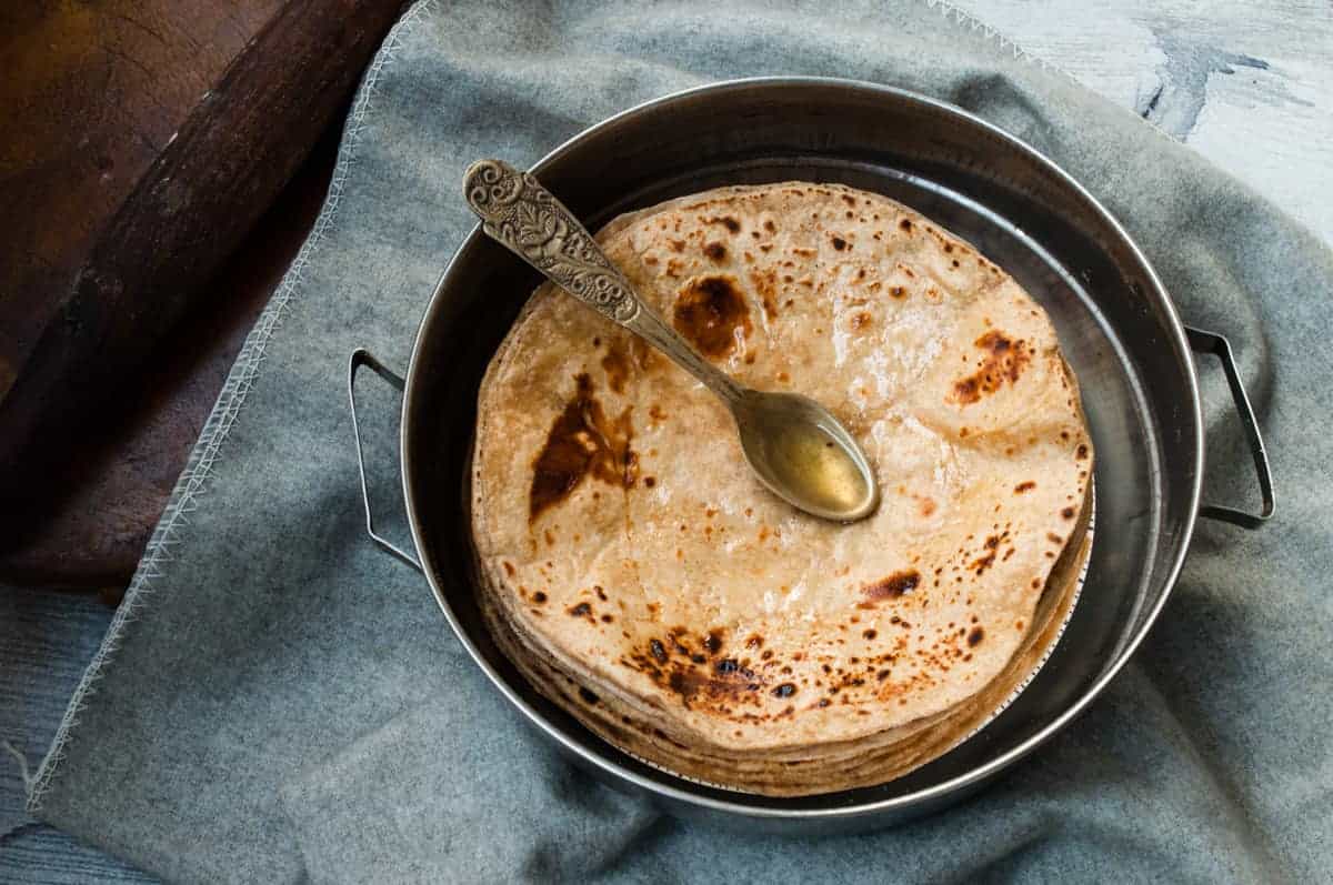 A spoon full of oil the pile of roti.