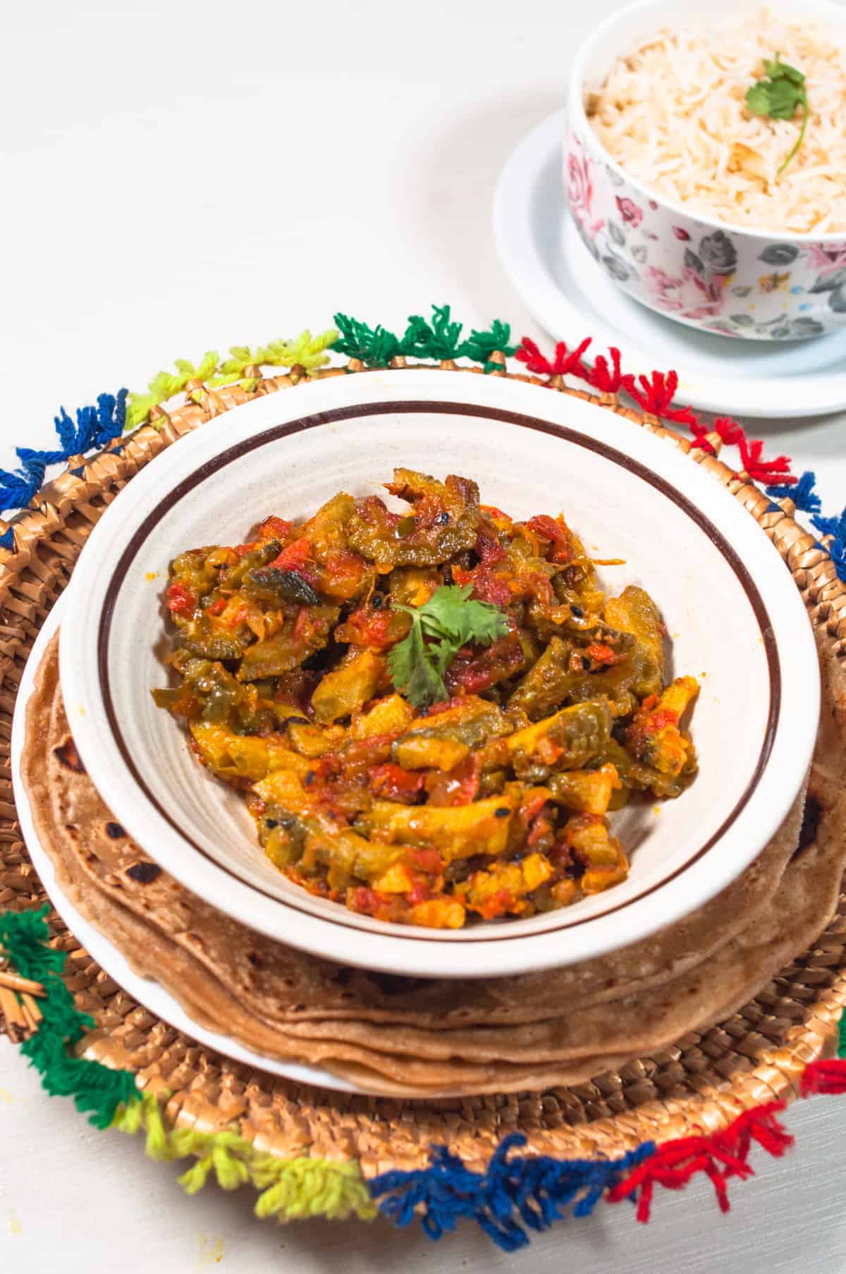 Karela served in bowl placed above a pile of roti.