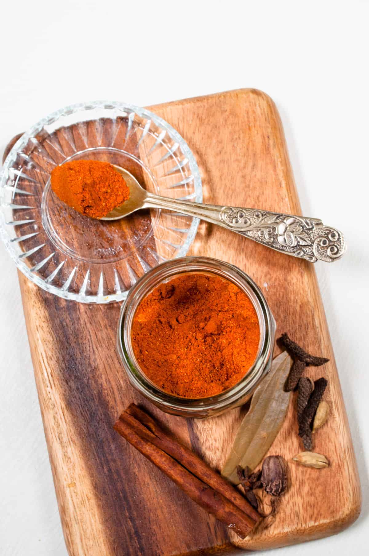 Nihari masala in a jar with whole spices on the side.