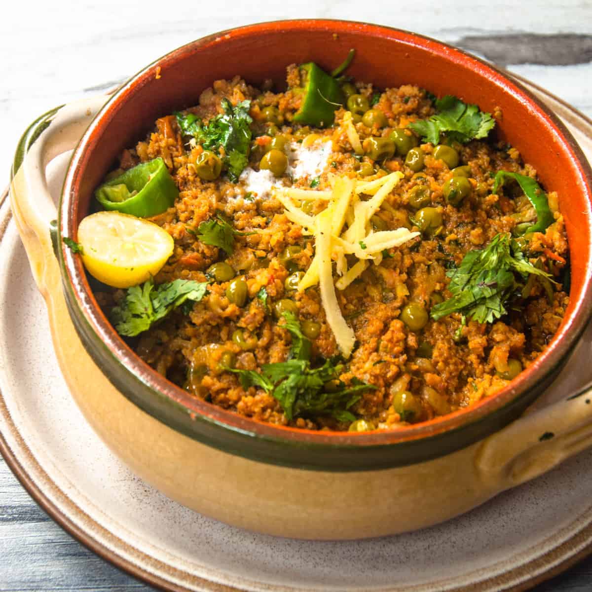 A close up shot  of Pakistani keema matar in a bowl  with garnish on it.