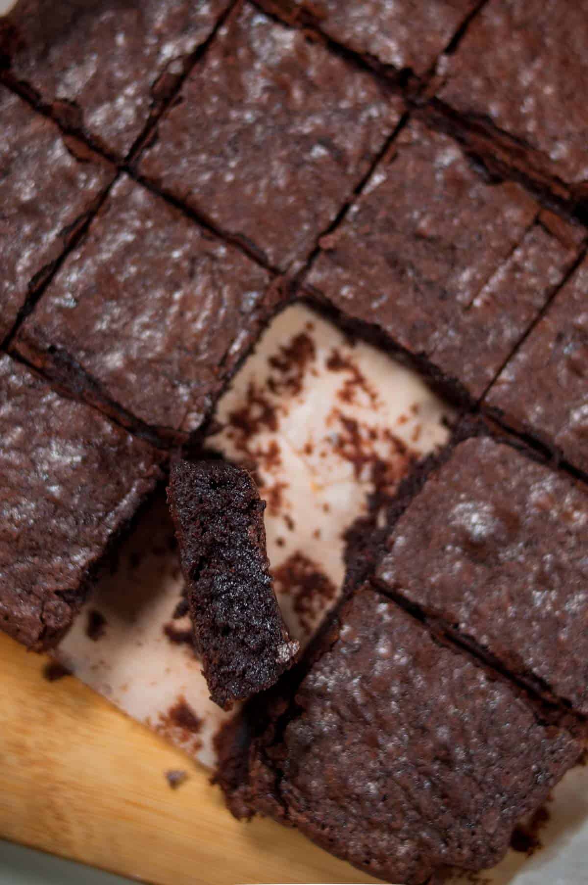 A slice of brownie kept vertically showing fudgy center in the brownie.