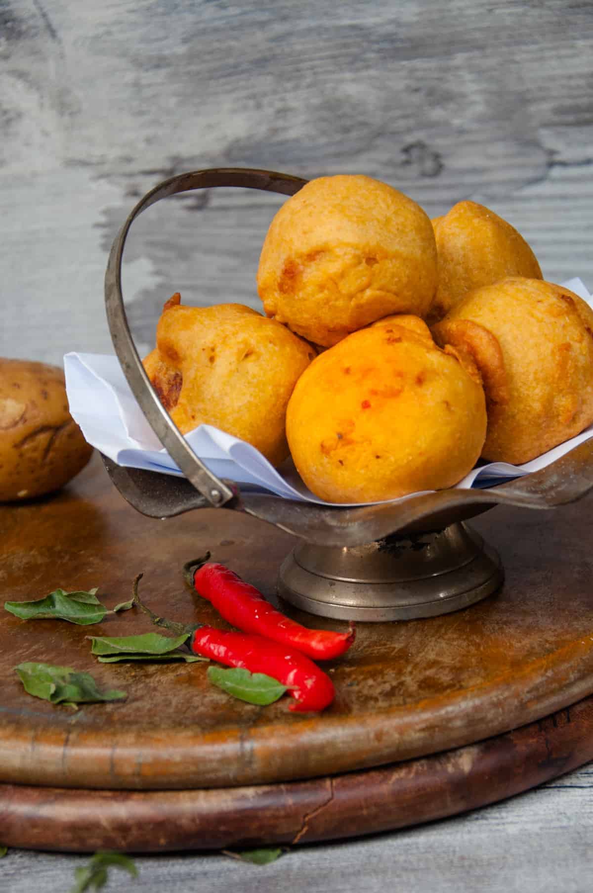 Batata vada served in metal basket.