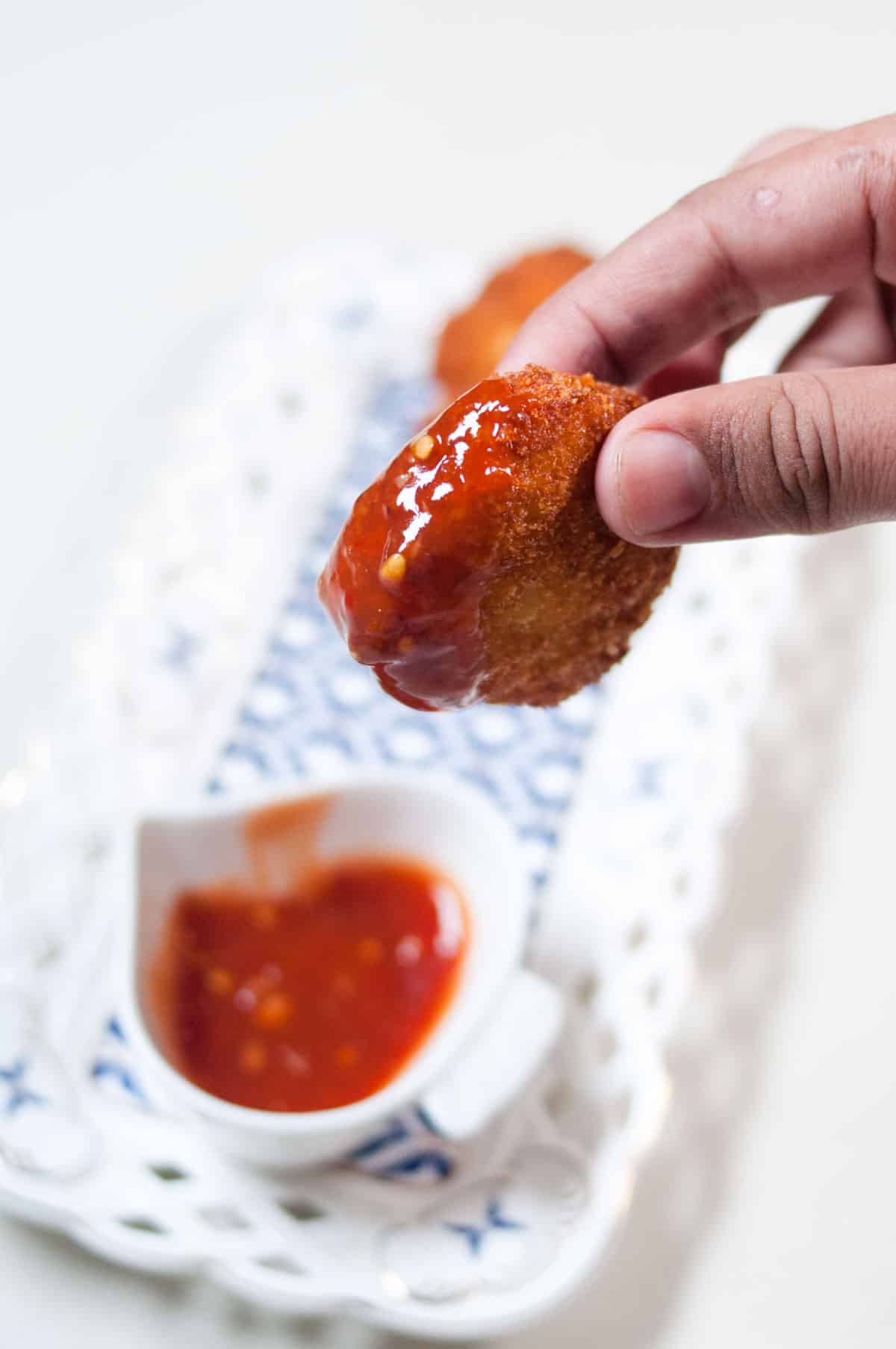 Ground chicken nuggets dipped in a sauce.