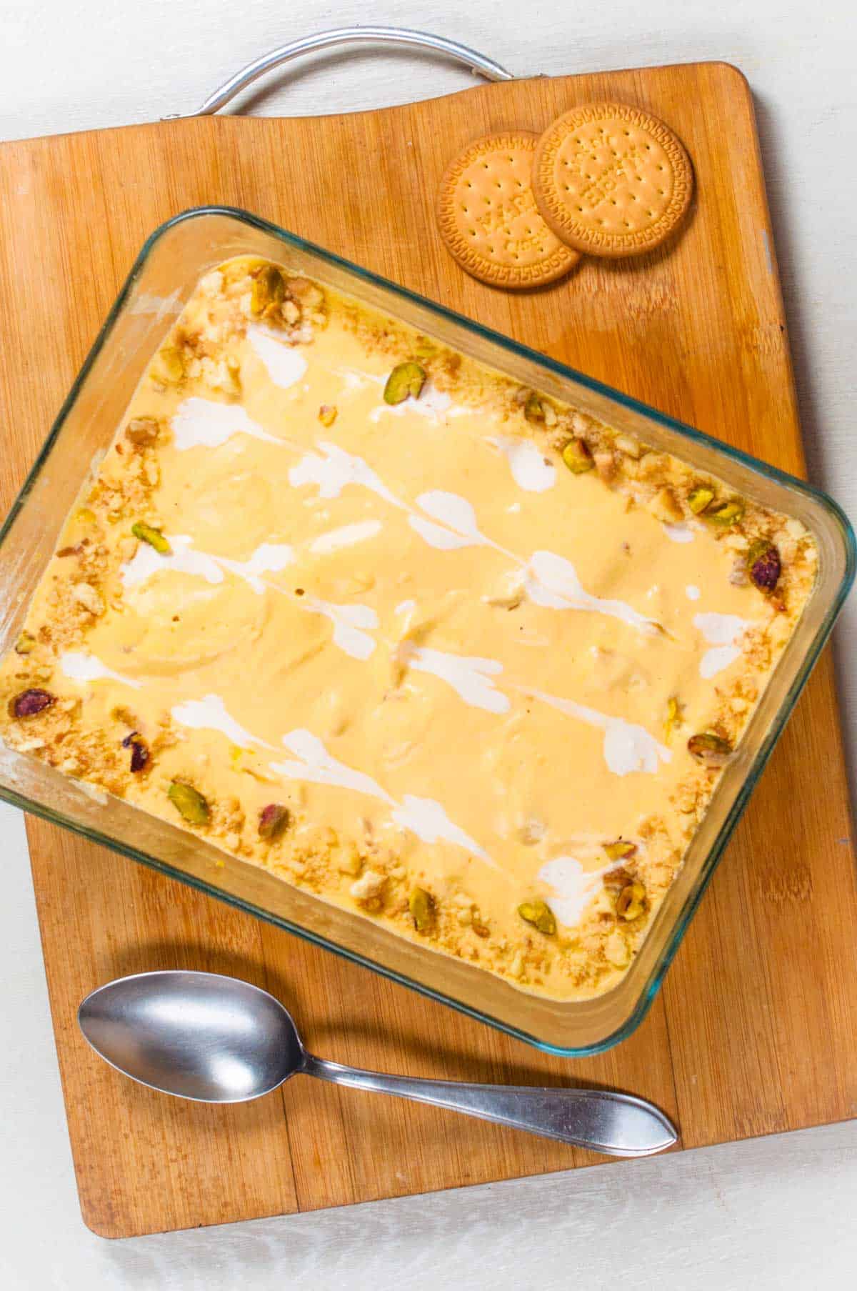 A large glass dish of Mango delight on the wooden board.