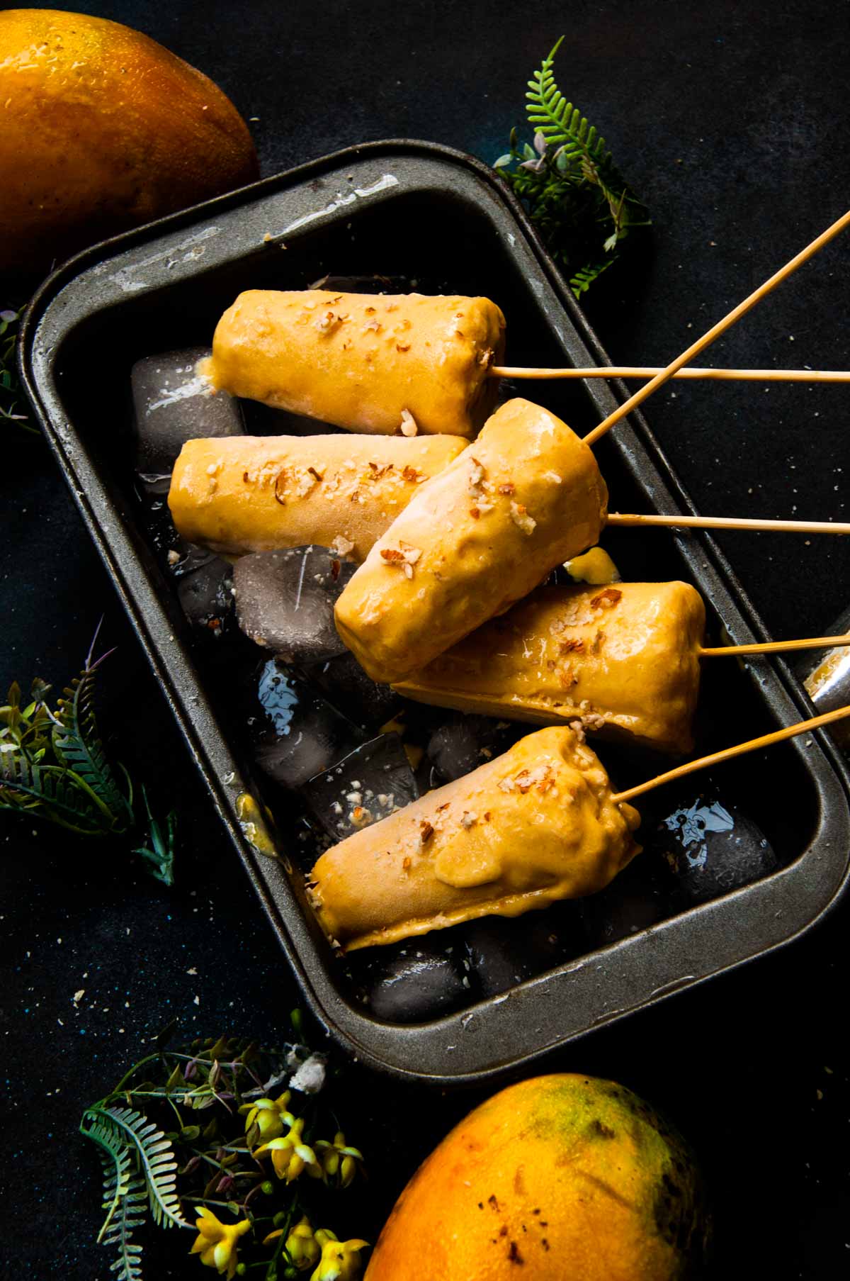 Mango kulfi served in loaf pan over ice cubes.