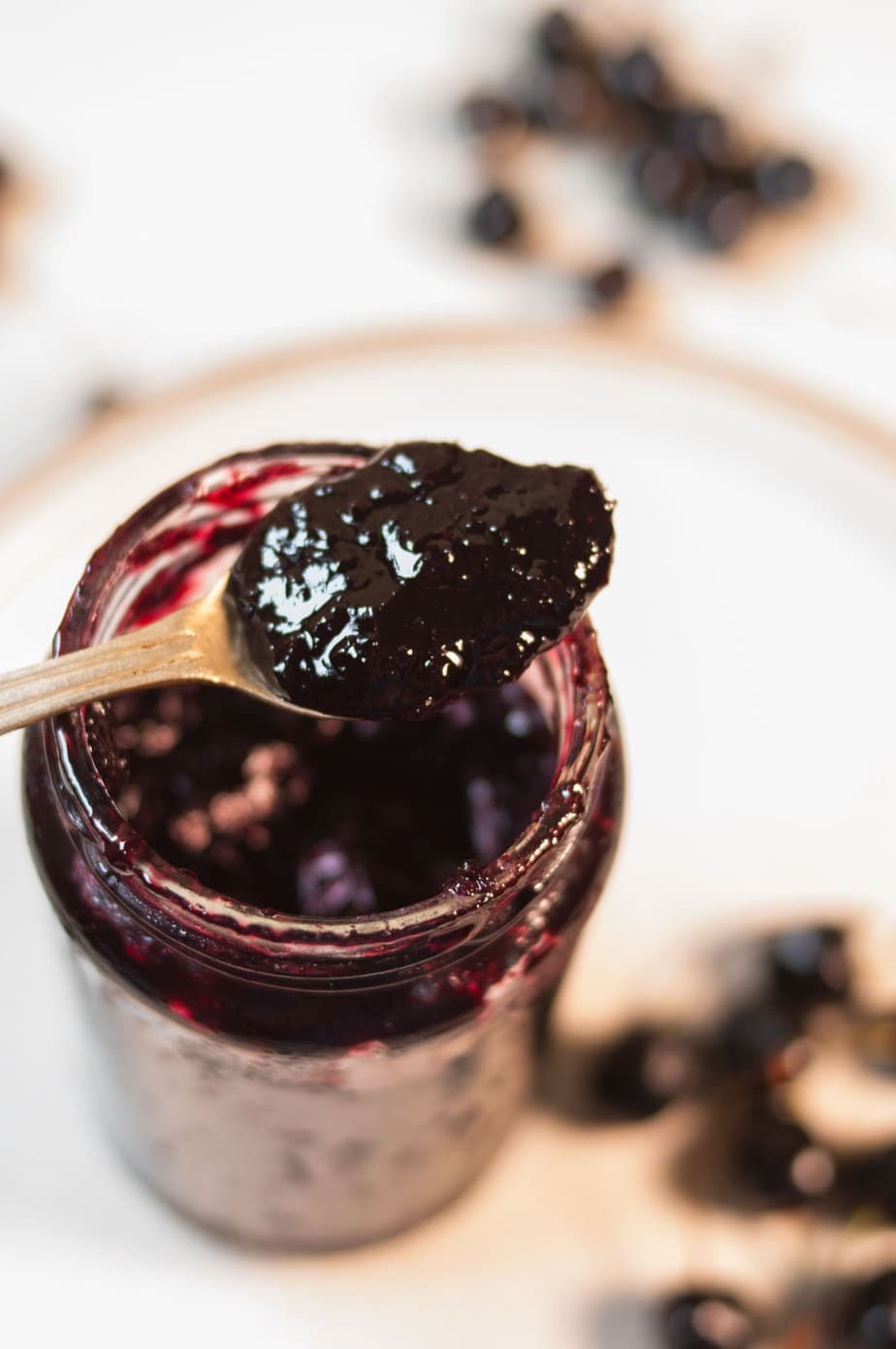 A spoon full of cherry jam resting on a jar.