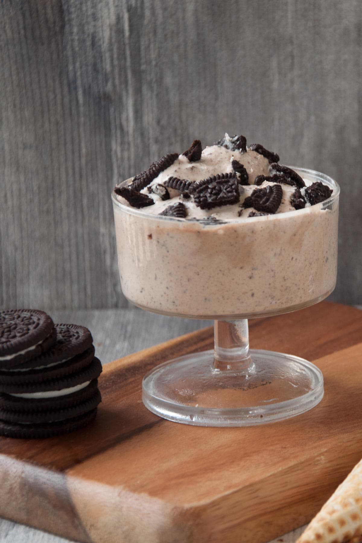 Oreo  Ice cream on a ice cream cup with oreo cookies topped over it.