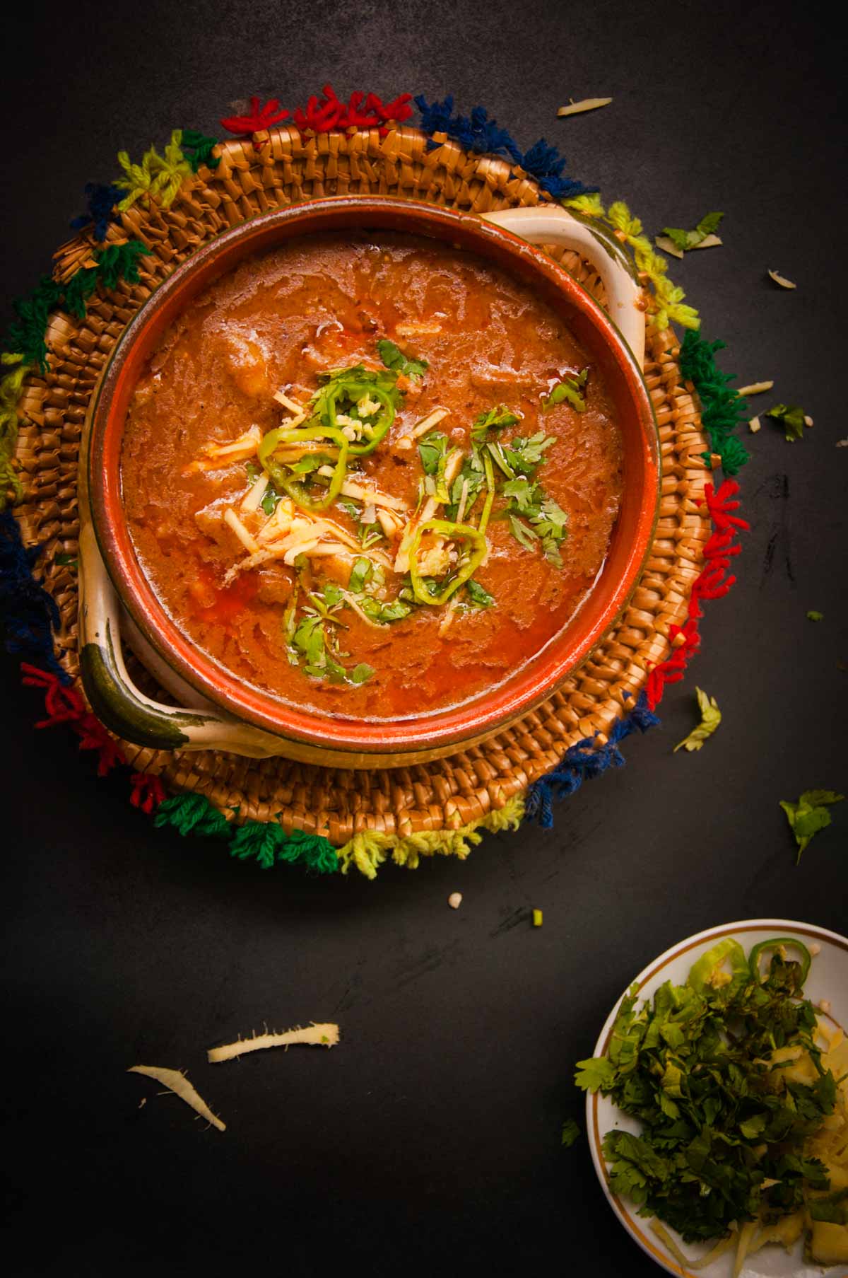 Nihari served in clay pot over black background.