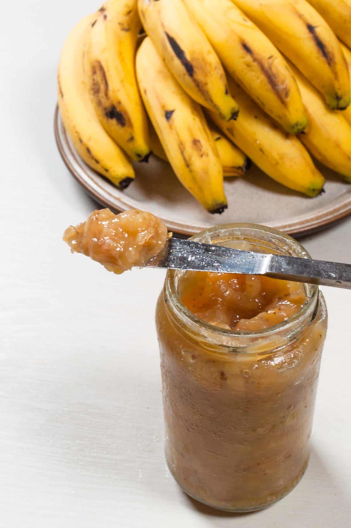 Banana on the breakfast knife kept on the jam jar. 