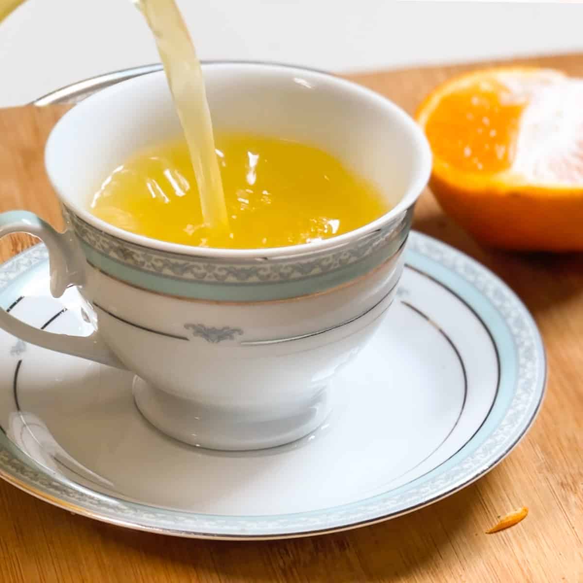 Orange tea being poured in the cup.