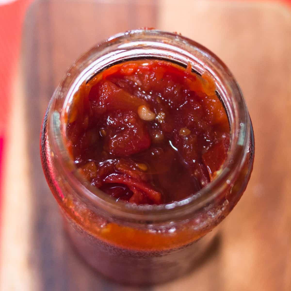 A close up shot of the tomato jam in an opened jar.