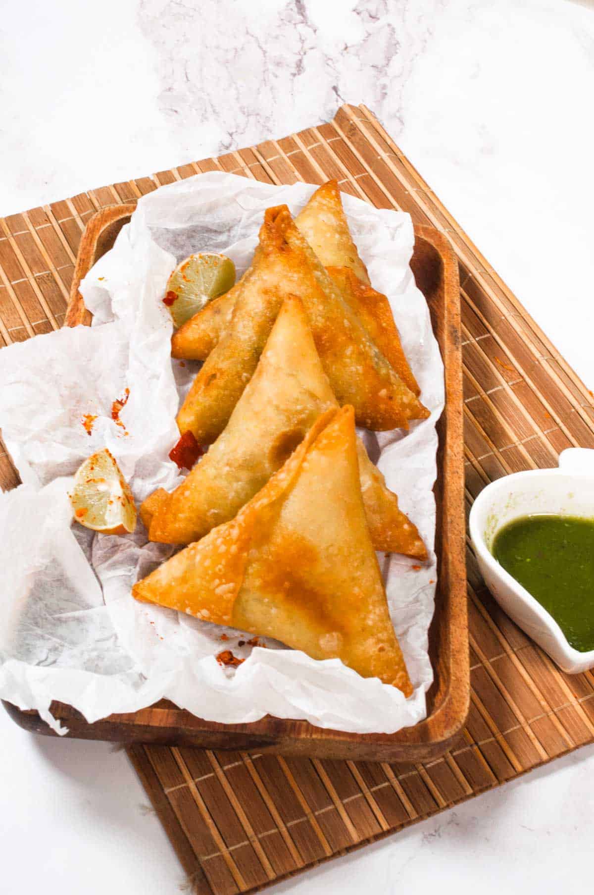 Four chicken samosa fried and lined up in a tray.