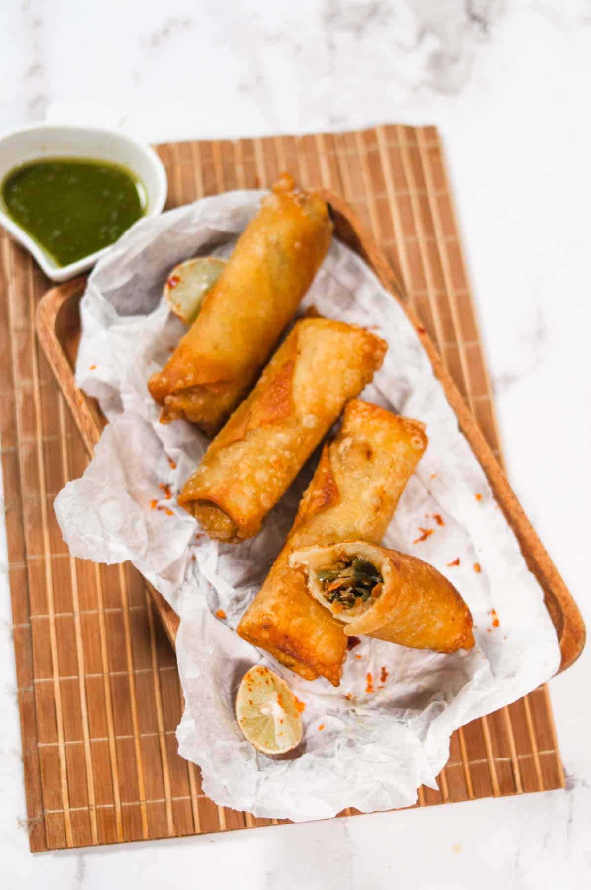 Chicken egg rolls on a paper over brown background mat.
