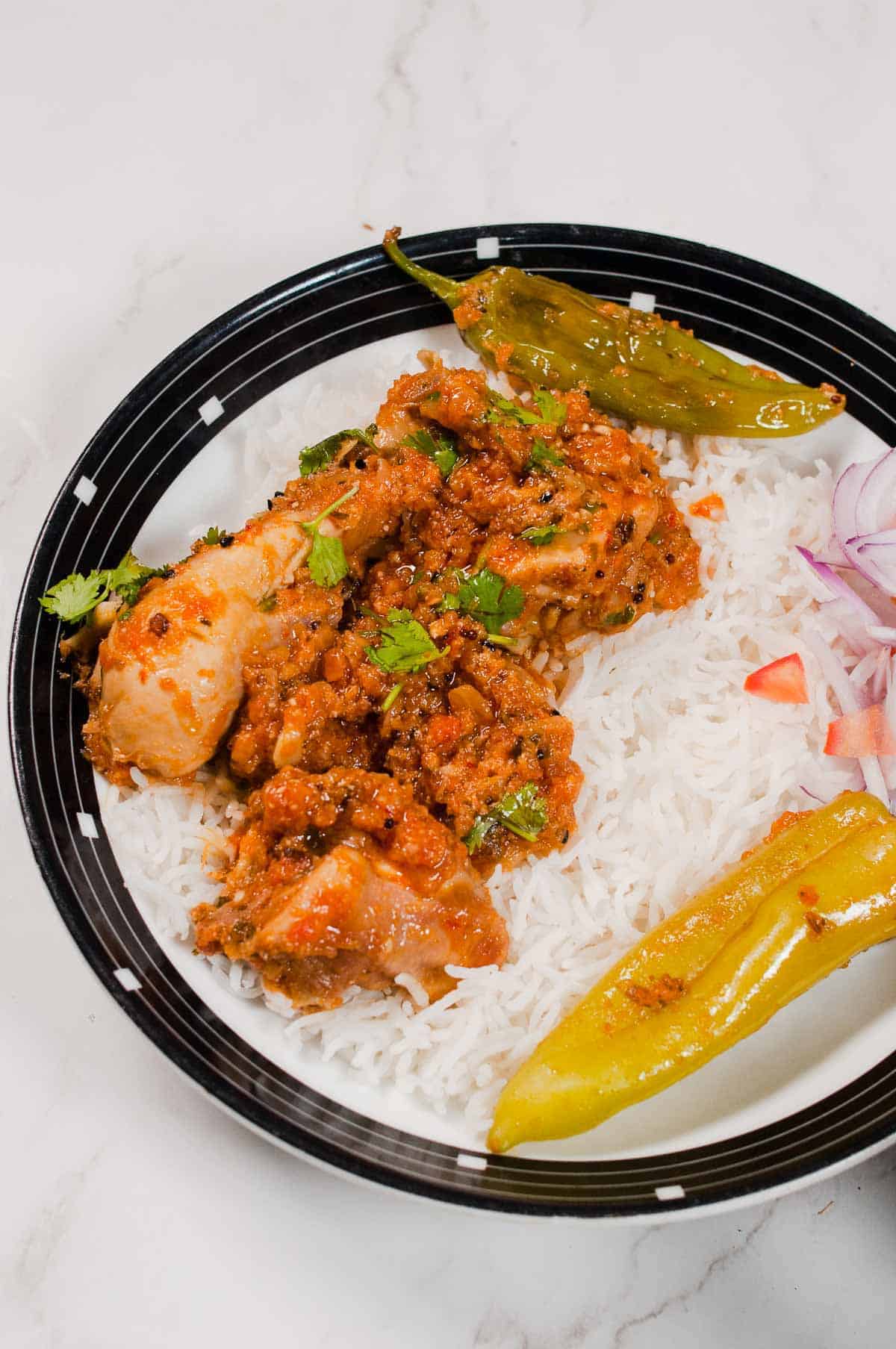 Achari chicken served with rice in a plate.