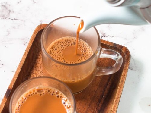 Indian chai in glass cups with metal kettle and other masalas to