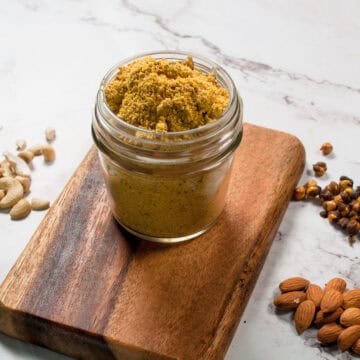 Kaari masala in a jar with nuts scattered around.