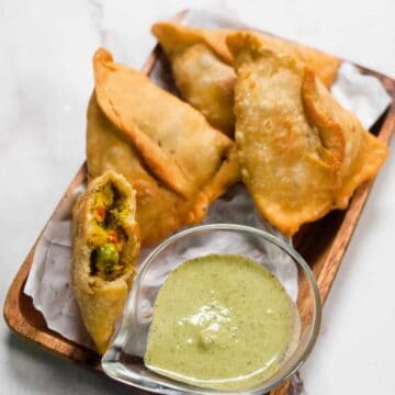 Samosa served in a wooden platter with chutney.
