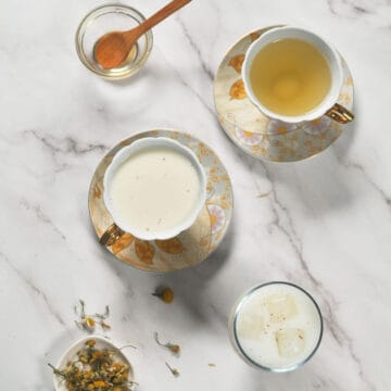 Three cups of tea sit on a marble surface