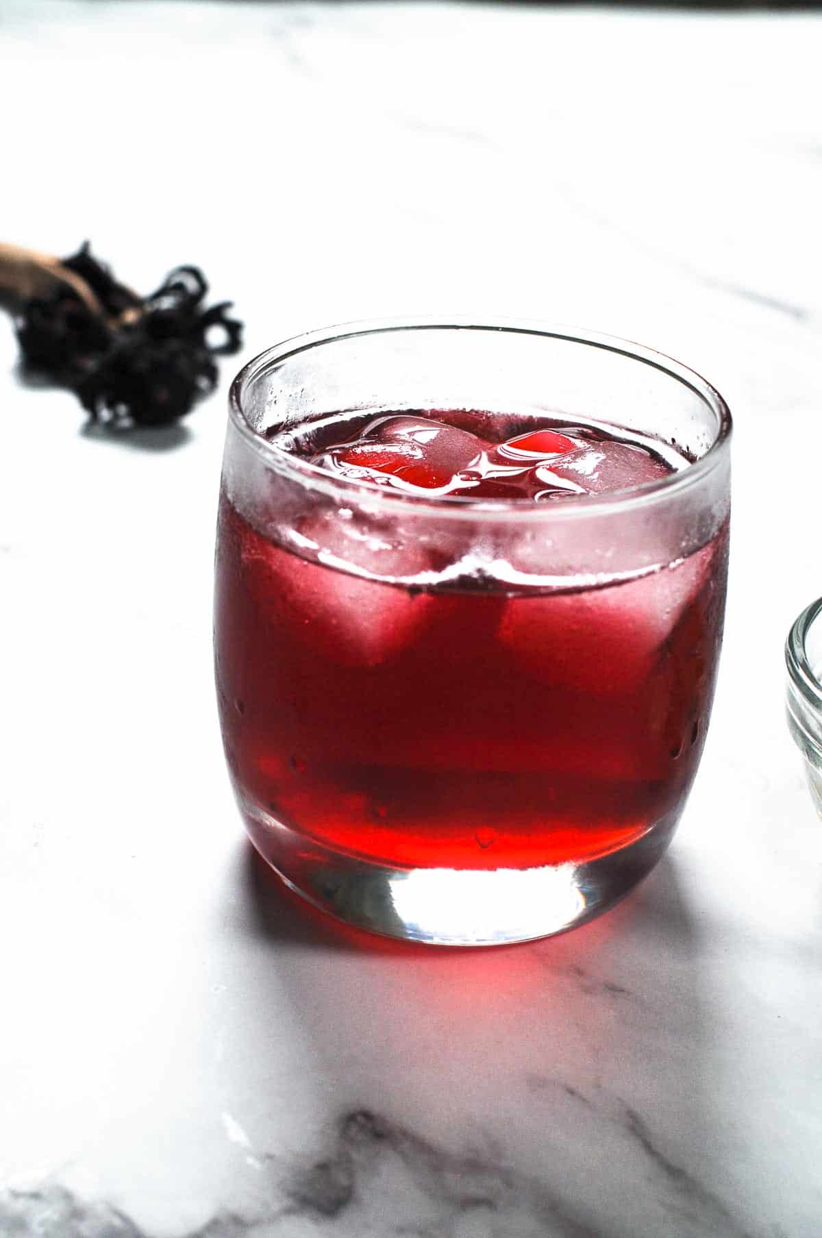 A glass of red hibiscus drink with ice.