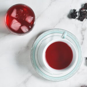 A cup of tea and a plate with dried hibiscus flowers.
